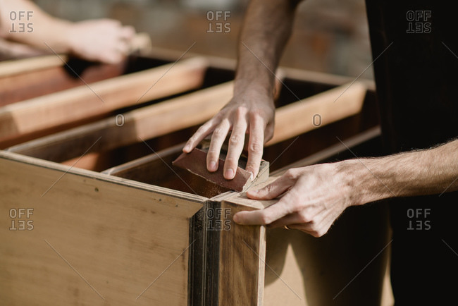 Hands sanding a dresser