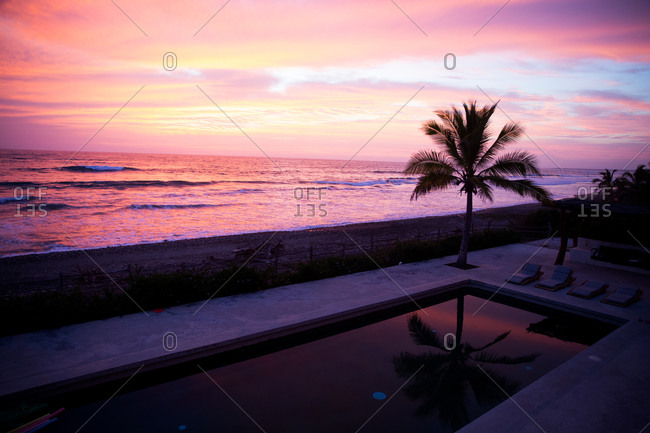 Beautiful pink sunset over oceanfront pool