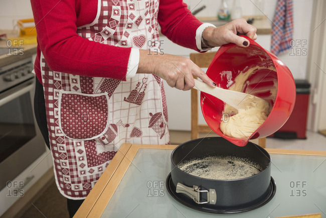 Senior woman pouring dough into a spring form pan, Munich, Bavaria, Germany