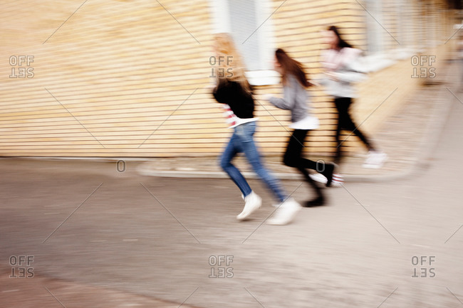 Three women running on street with building in background