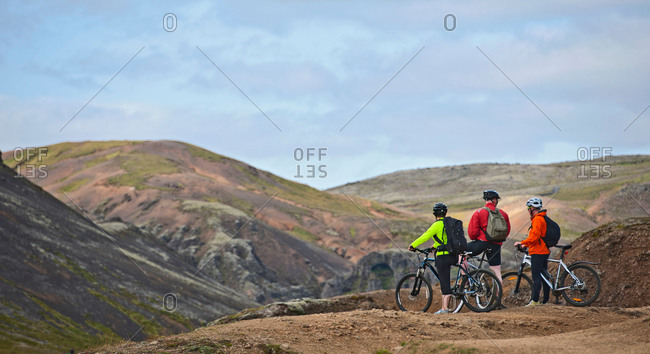 Three mountain bikers taking a break at viewpoint,  Reykjadalur valley, South West Iceland