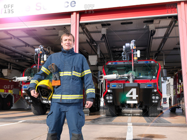Portrait of fireman in front of fire engines in airport fire station
