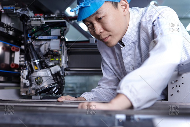 Worker using machinery in factory that specializes in creating functional circuits on flexible surfaces