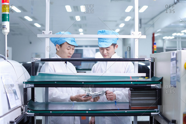 Workers using machinery in factory that specializes in creating functional circuits on flexible surfaces