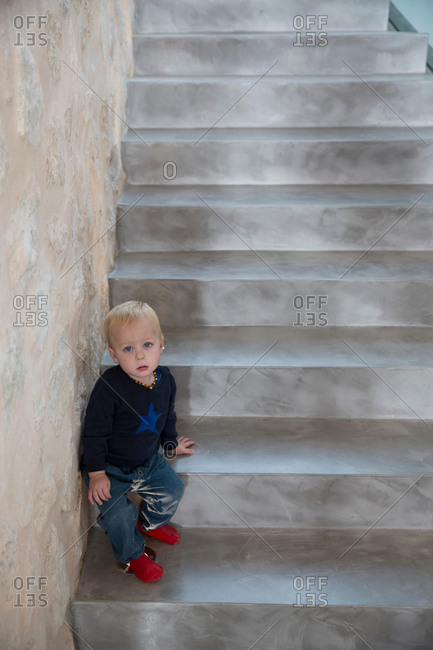 Portrait of male toddler sitting on house staircase