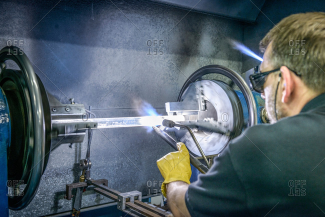 Industrial glass blower forming a tube on lathe