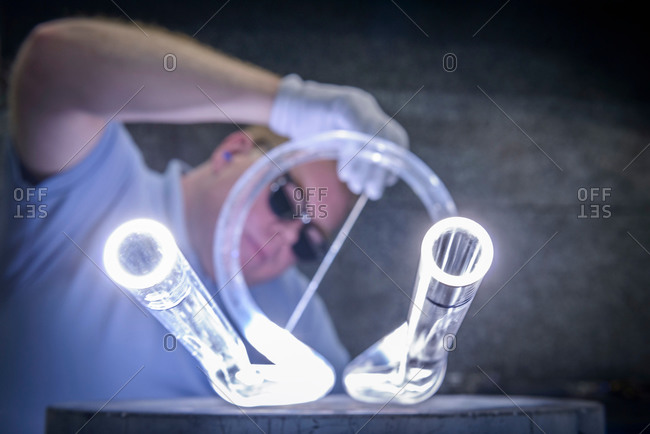 Industrial glass blower welding glass tubes