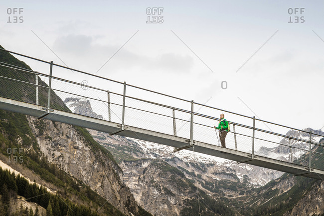 Low angle view of young woman hiking on footbridge, Holzgau, Tirol, Austria