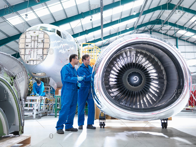 Engineers working on engine in aircraft maintenance factory