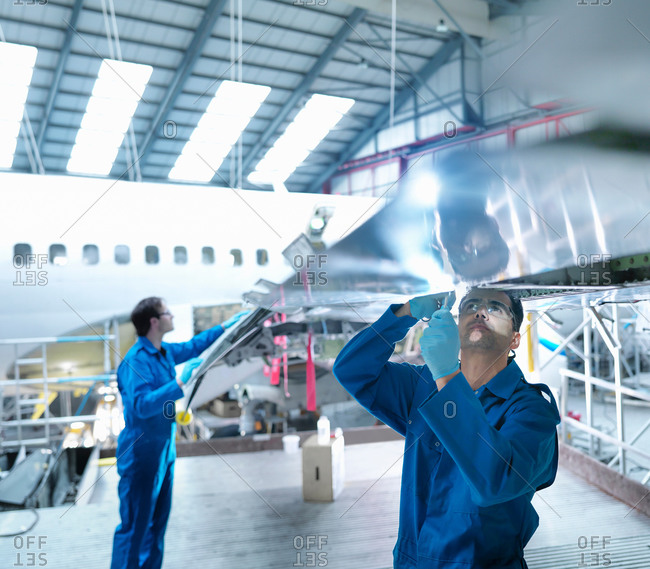 Engineers working on wing in aircraft maintenance factory