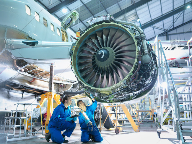 Aircraft engineers inspecting jet engine in aircraft maintenance factory