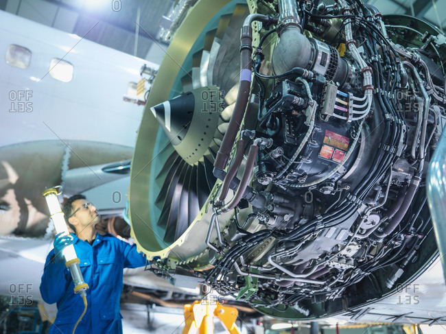 Engineer inspecting jet engine in airplane maintenance factory