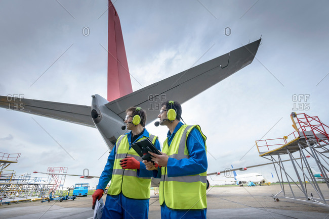 Airside engineers checking jet aircraft on runway