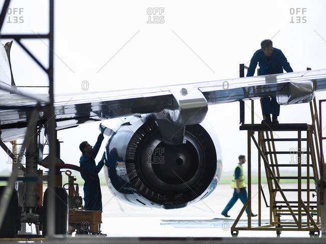 Engineers working on aircraft wing in aircraft maintenance factory