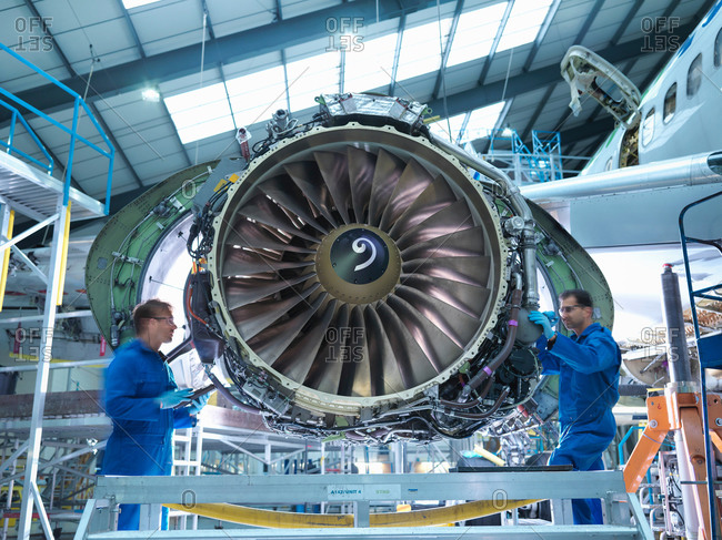 Engineers working on aircraft engine in aircraft maintenance factory
