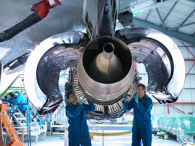 Engineers working on jet engine in aircraft maintenance factory