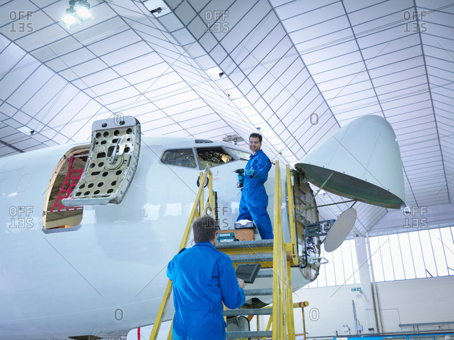 Engineers working on airplane in aircraft maintenance factory