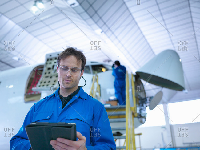 Engineer using digital tablet in aircraft maintenance factory