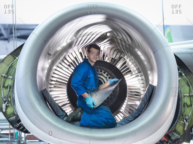 Portrait of an engineer holding jet engine turbine blade in aircraft maintenance factory