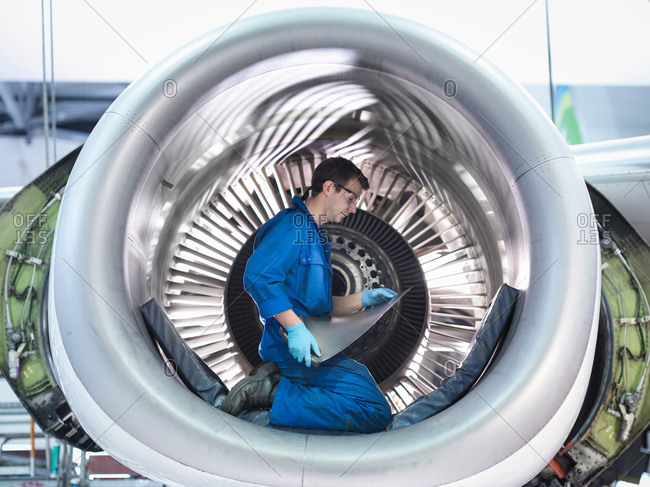 Engineer holding jet engine turbine blade in aircraft maintenance factory