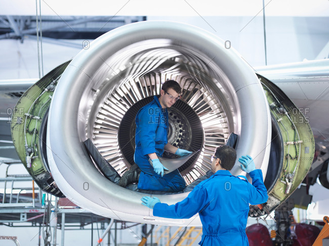 Engineers working with jet engine turbine blade in aircraft maintenance factory