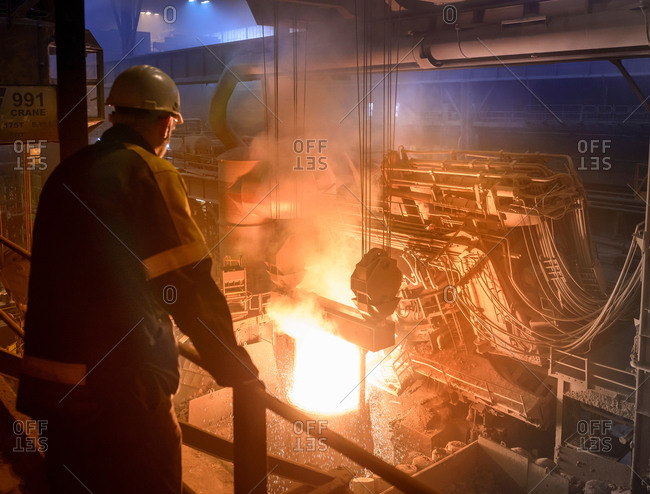 Steel worker inspecting pouring molten steel