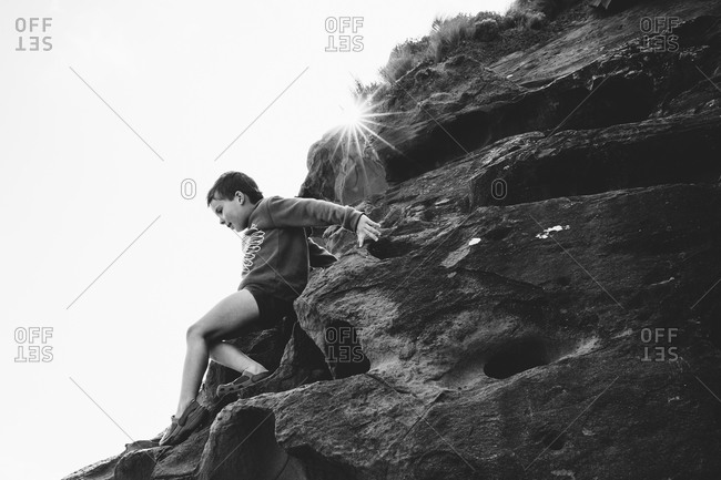 Boy climbing down the side of a steep rocky hill