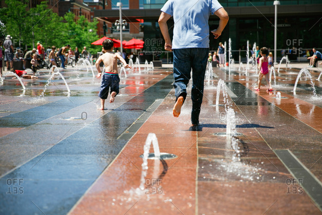 Boy and man running through fountain