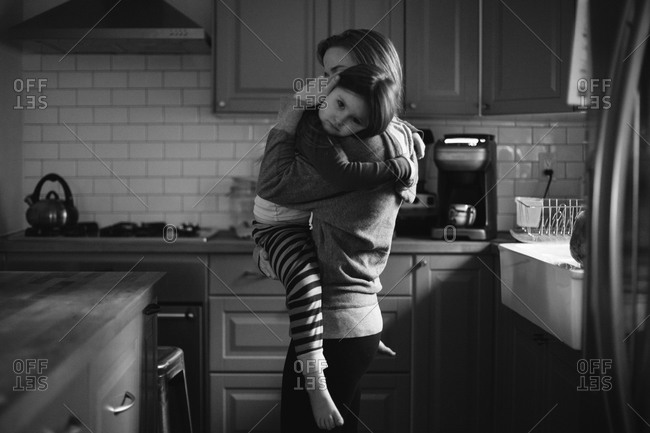Mother holding and comforting daughter in the kitchen