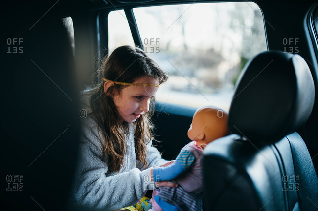 Girl in back seat of car playing with her doll