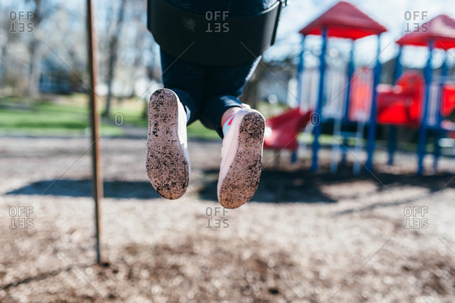 Bottoms of a child\'s shoes on a swing