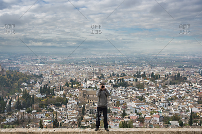 Caucasian tourist on wall over scenic view of cityscape, Granada, Spain