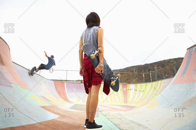 Woman holding skateboard at skate park