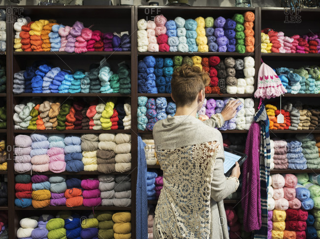 Caucasian entrepreneur taking inventory in yarn store