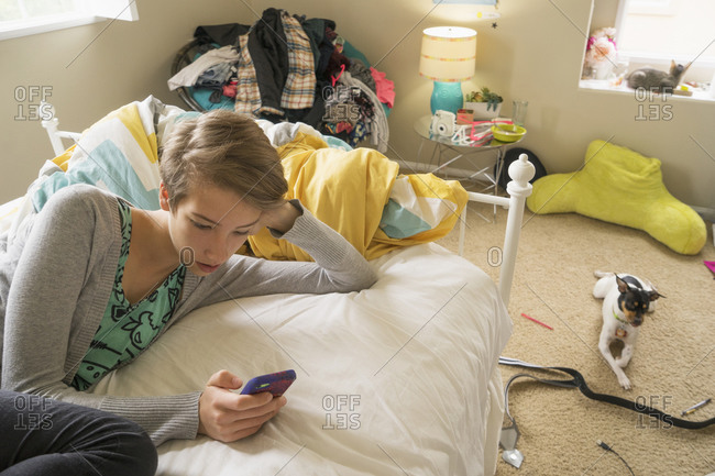 Caucasian girl using cell phone on bed