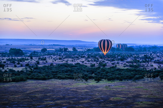 Hot air balloon flying over savanna landscape