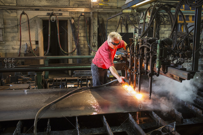 Caucasian worker spraying machinery in factory