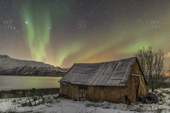 The Northern Lights illuminates the wooden cabin Svensby Lyngen Alps Tromso Lapland Norway Europe