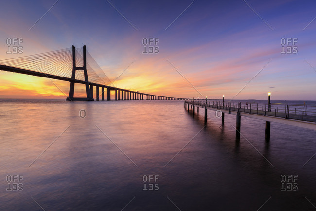 The colors of dawn on Vasco da Gama Bridge that spans the Tagus River in Parque das Na?_?�es Lisbon Portugal Europe
