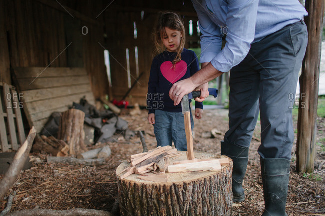 Father teaching daughter how to split firewood