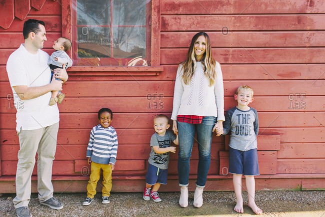 Blended family standing by a red building
