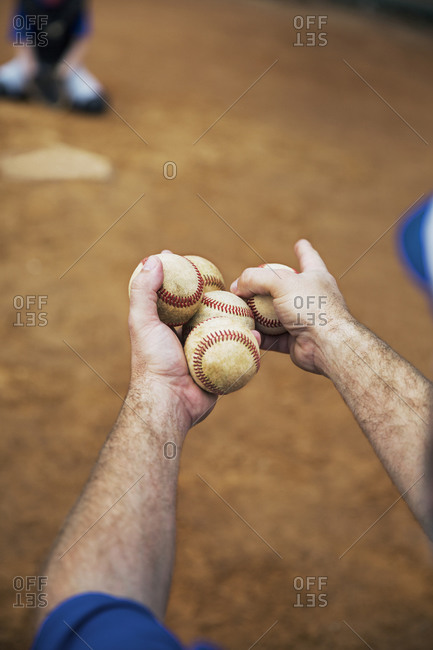 Cropped image of coach holding baseballs on field