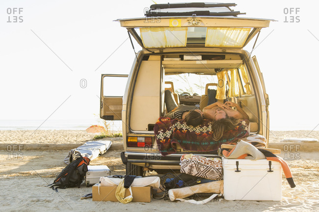 Young couple lying in mini van during summer vacation on San Onofre State Beach