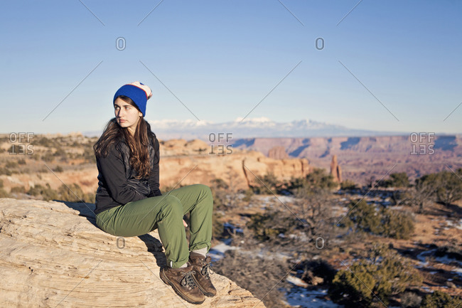 A young woman rests on a rock in the desert southwest of the US