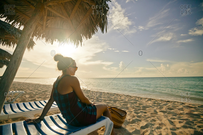 A young woman relaxing on the beach under a beach umbrella in Cayo Coco, Cuba