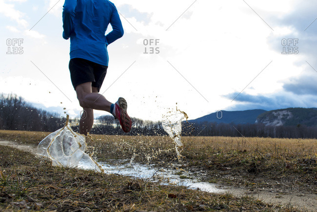 Trail runner splashing through a puddle