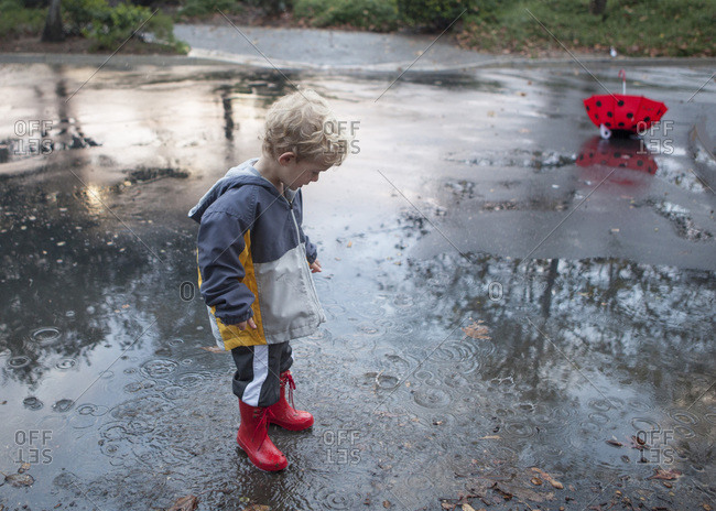 Boy in rubber boots plays in puddle