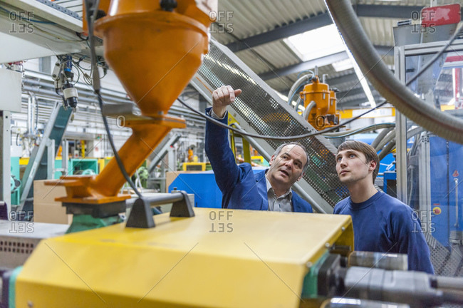 Two people in plastics factory examining a machine
