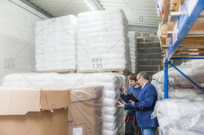 Manager and worker in storage of plastics factory checking products before shipping