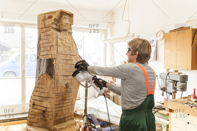 Wood carver working on sculpture with chainsaw